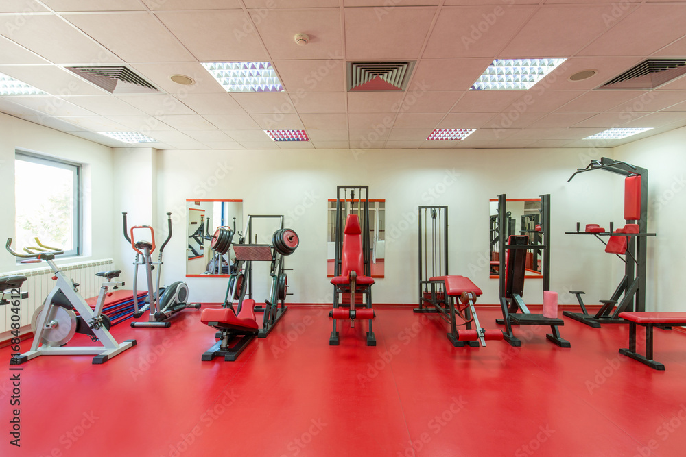 Fototapeta premium Interior of a modern hotel gym with exercise equipment and red floor