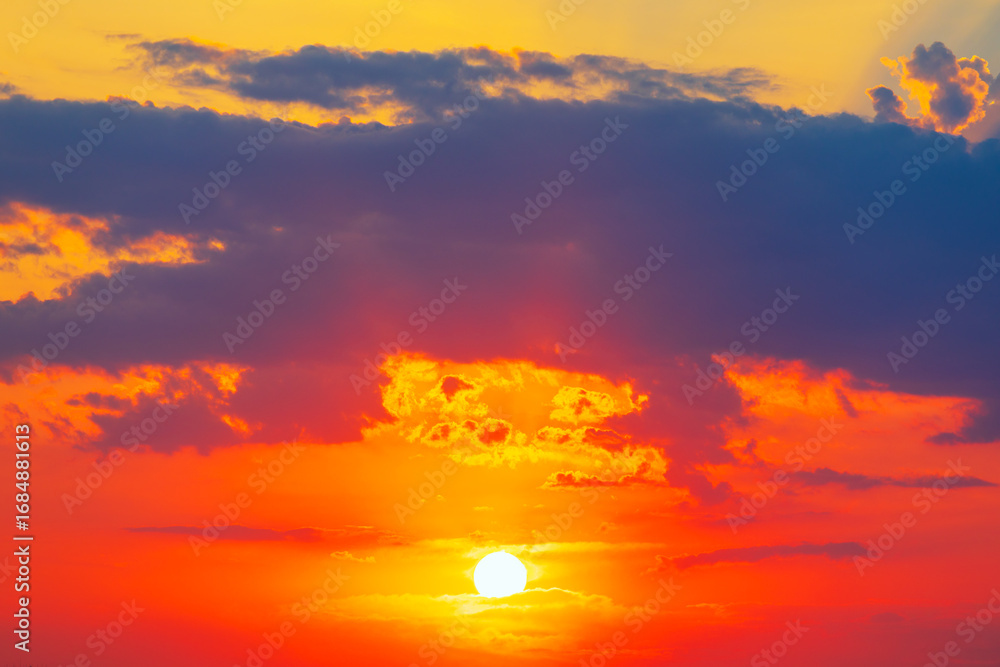 Obraz premium Sky with sun dips below the horizon. Scattered clouds catch the light, adding depth and drama to this vivid, tranquil sunset scene