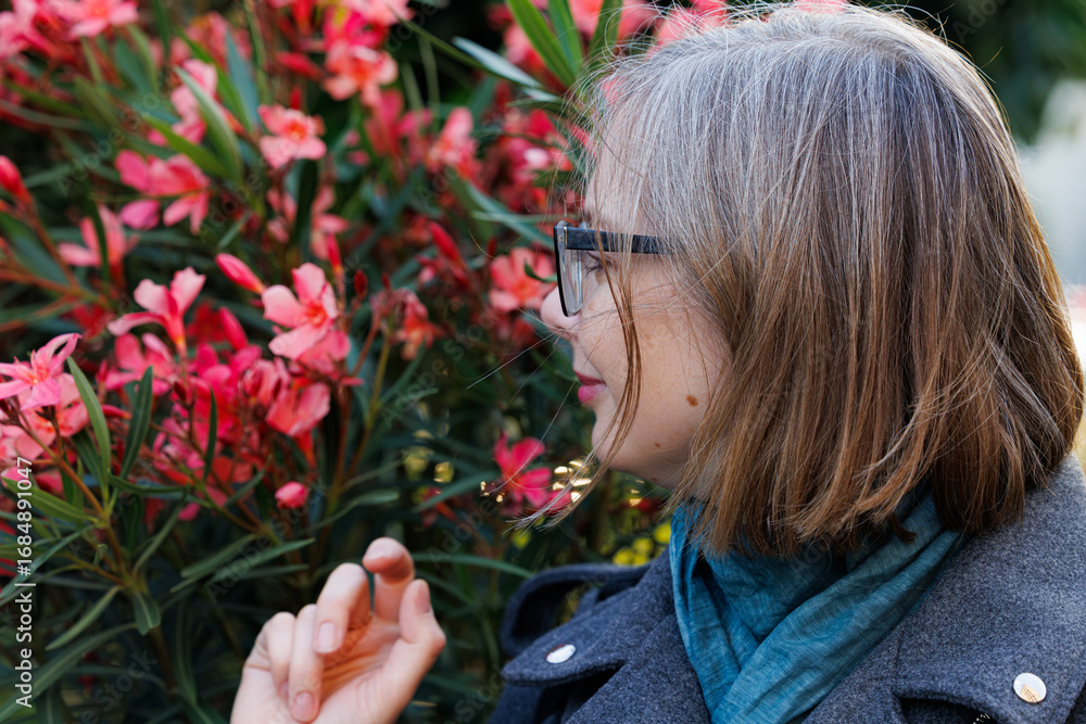Fototapeta premium Woman enjoying spring flowers in a vibrant garden, immersed in the beauty of nature