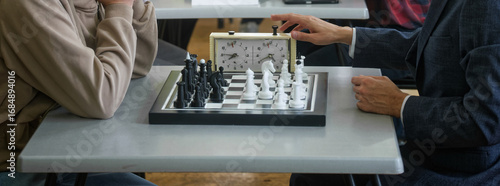 Billede på lærred Grandmaster in a suit hits the chess clock after a move against an opponent; time pressure and strategy drive the duel—business‑style decision for gain