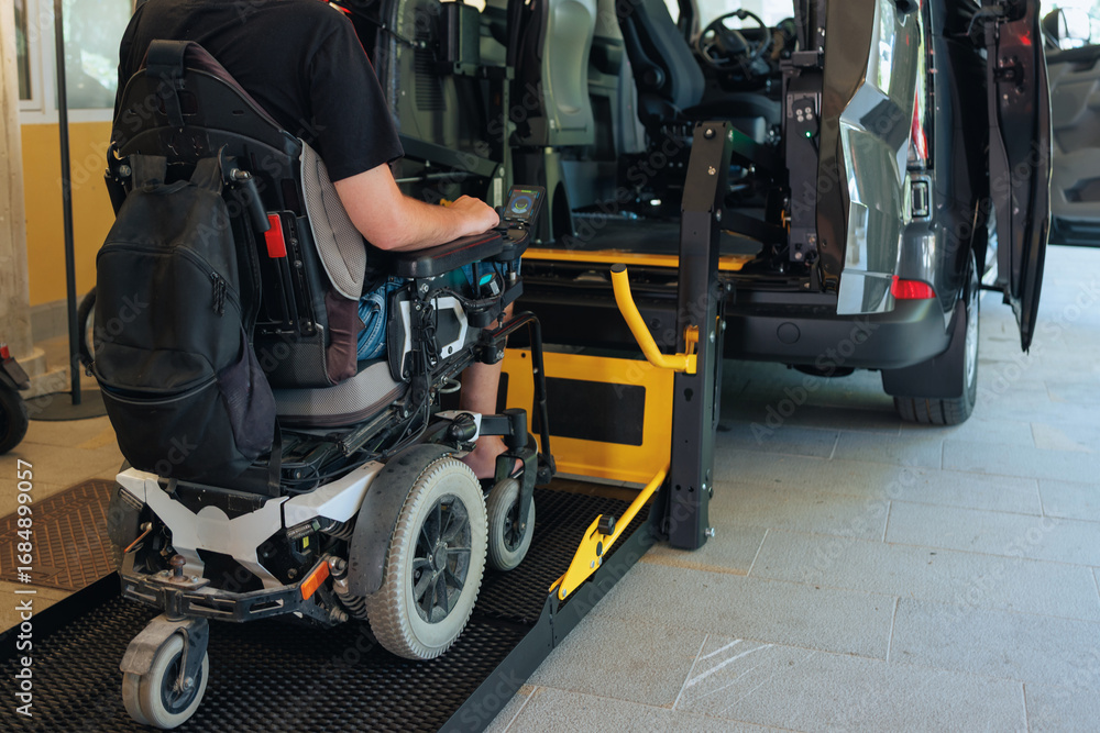 Obraz premium Person with disability is using a wheelchair ramp to enter a vehicle at a transportation facility during daytime for mobility assistance.