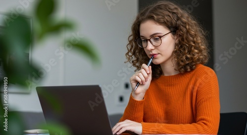 Woman working on laptop pensive expression indoor setting