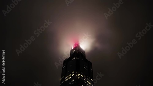 Skyscraper aircraft warning lights blink in synchronized rhythm through thick nocturnal fog, a mesmerizing urban beacon.