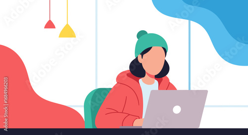A focused person in a beanie and hoodie works remotely on a laptop. Ideal for themes of productivity, online learning, work-from-home, or creative professional lifestyle.