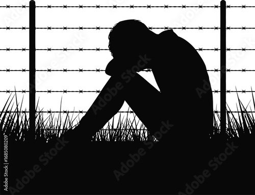 Silhouette of a person sitting in despair behind a barbed wire fence