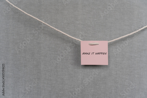 Pink note hanging on the rope with the inscription make it happen