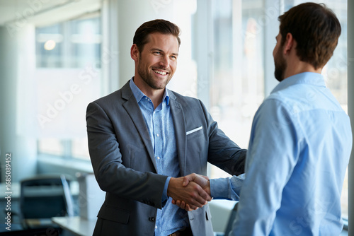 Happy young businessman welcoming a new colleague with a handshake
