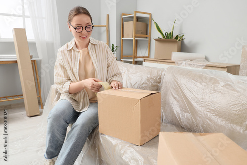 Young woman taping box in r...