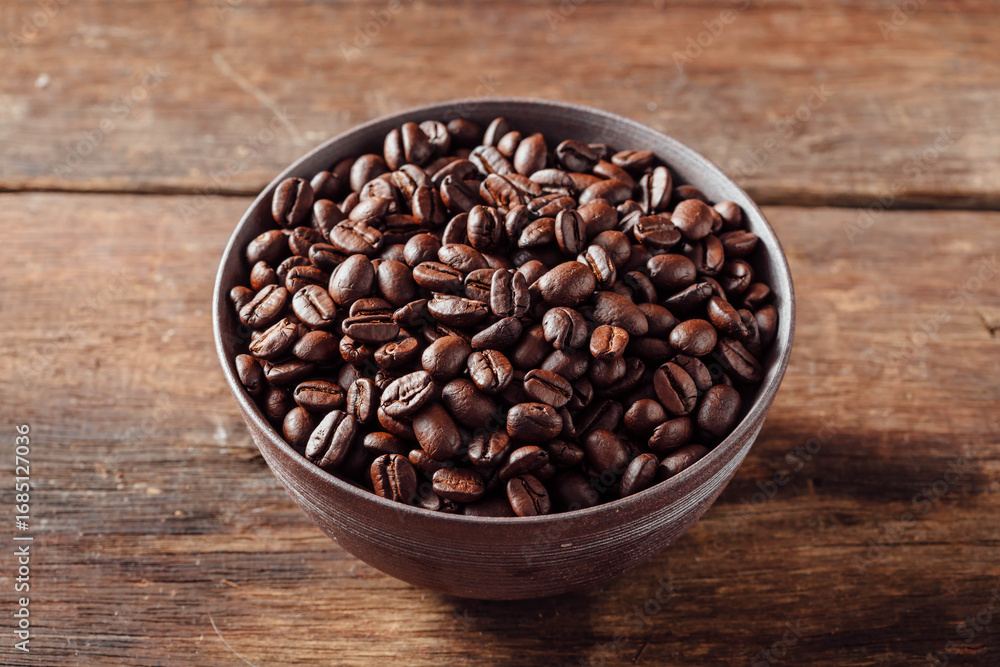 Fototapeta premium Freshly Roasted Coffee Beans in Rustic Bowl on Wooden Surface