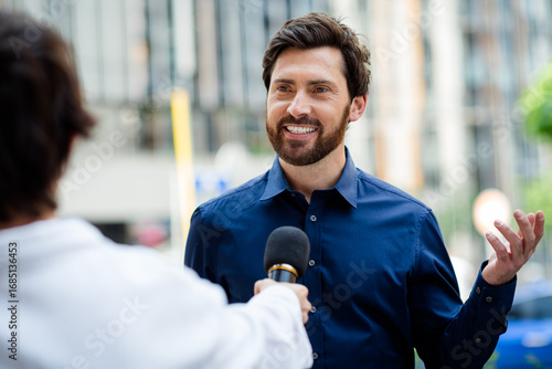 Obraz na plátne Confident male professional being interviewed outdoors with urban background con