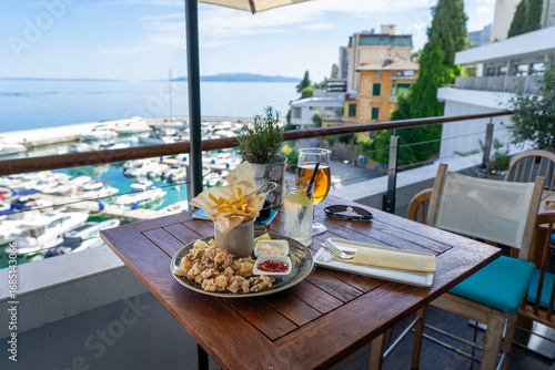 eating fried squid calamari with a sea view from balcony in croatia with drinks