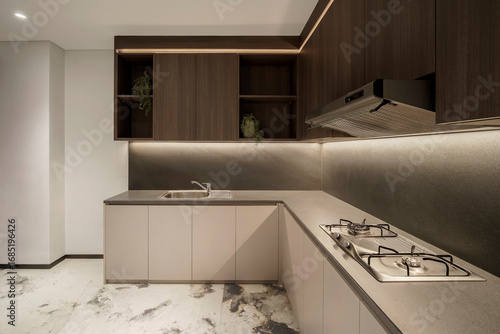 Modern L-shaped kitchen with gas stove, sink, and dark wood cabinets with open shelves holding potted plants. Backlit with warm LED strip lights.
