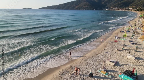 Woman walking on Golden beach near sea at Thassos Island, Greece. Amazing beach with clear blue water. Aerial panoramic drone view from above, top view from drone. Summer holidays Europe
