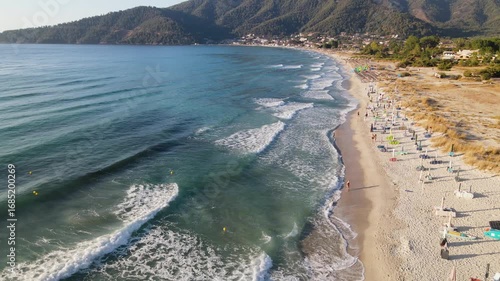 Woman walking on Golden beach near sea at Thassos Island, Greece. Amazing beach with clear blue water. Aerial panoramic drone view from above, top view from drone. Summer holidays Europe
