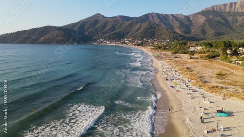 Woman walking on Golden beach near sea at Thassos Island, Greece. Amazing beach with clear blue water. Aerial panoramic drone view from above, top view from drone. Summer holidays Europe
