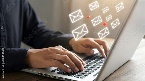 Man actively typing on a laptop as email icons float upwards, signifying digital communication and online messaging.