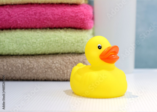 Yellow rubber duck with towels in the background