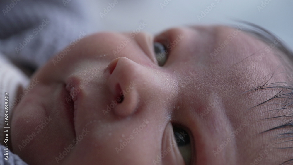 Fototapeta premium Newborn's face in close-up with eyes wide open, curiosity and innocence of early life, emphasizing the delicate skin and fine details of the baby's facial features