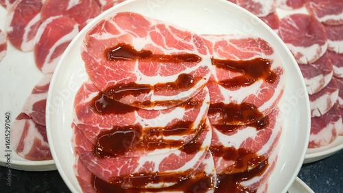 Photos Sliced pork or beef meat with spicy sauce which is served in white plate, prepare for Yakiniku grilling meal
