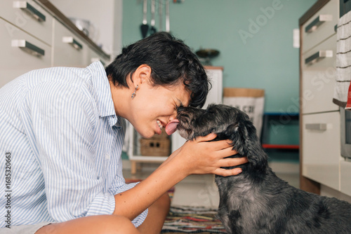 Young girl showing love to her pet by kissing and hugging it in the kitchen