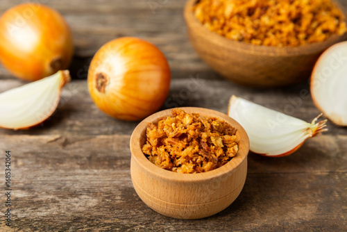 Crispy fried onions in a bowl on a wooden table. Roasted Onions. Seasoning for dishes. Spices. Salad dressing. Space for text. Copy space