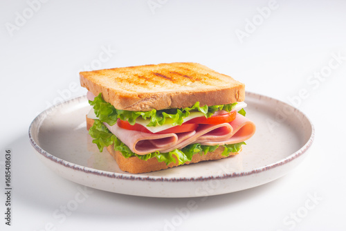 Close-up of two sandwiches with bacon, salami, prosciutto and fresh vegetables on rustic wooden cutting board. Club sandwich concept