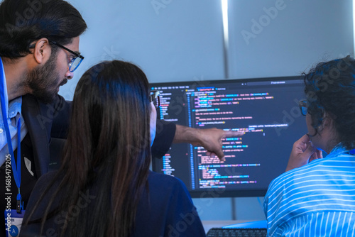 Obraz na plátne A manager leads a team meeting in a modern office, pointing to the computer screen to explain a project