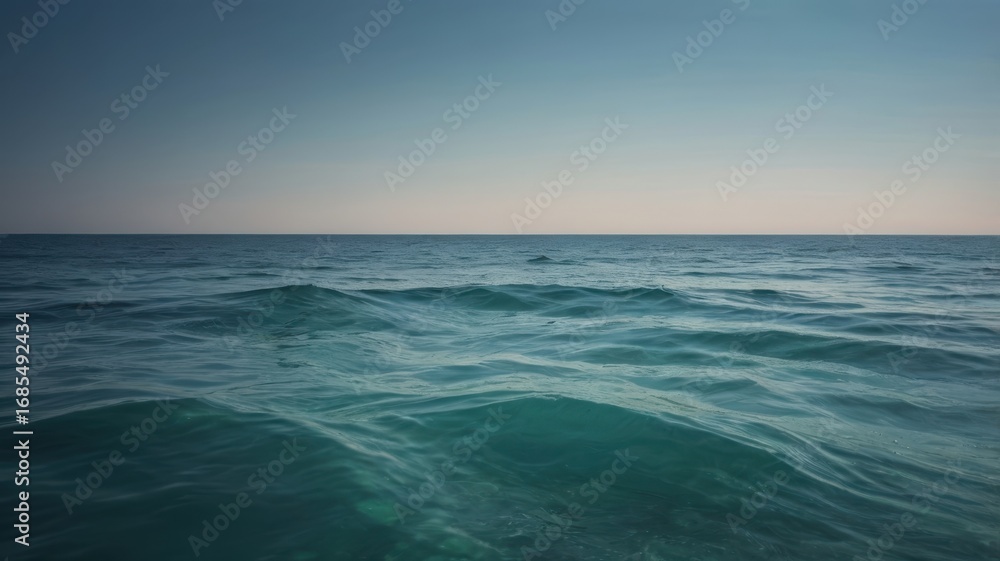 Fototapeta premium Tranquil Teal Ocean Waves Under a Pale Blue Sky at Dusk