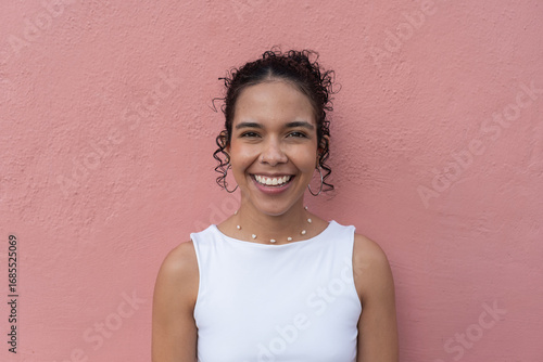 Young latin woman smiling over pink background