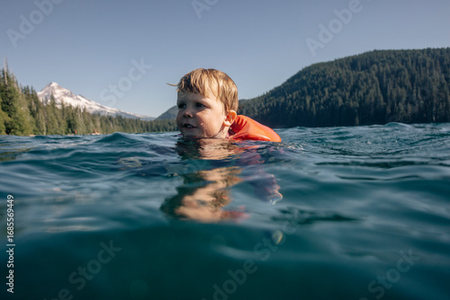 A young toddler swims in an alpine lake in the Pacific Northwest.