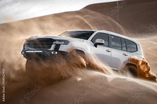 White SUV driving through desert sand, Saudi Arabia