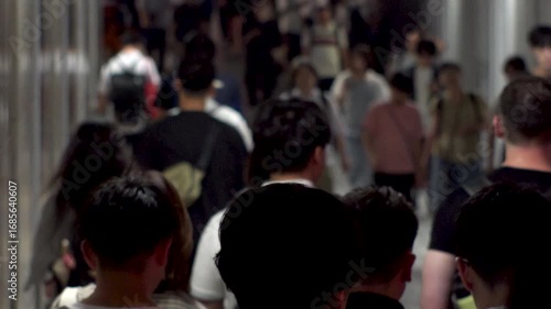 TOKYO, JAPAN - AUG 2025 : Crowd of people walking at the street near the station in busy night rush hour. Japanese people, urban city life and lifestyle concept video. Slow motion shot.