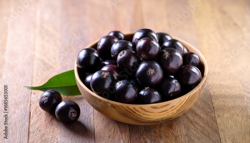 jaboticaba berries in a bowl on a wooden surface