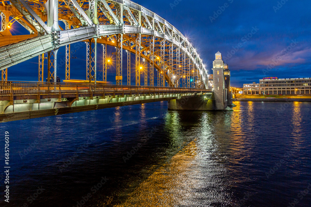 Naklejka premium Dusk perspective view of illuminated Bolsheokhtinsky Bridge with lights reflection in rippling Neva River water. Saint Petersburg, Russia.
