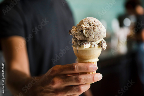 Person holding ice cream cone with two scoops