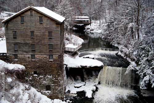 Mill Creek park in Youngstown, Ohio in winter with an old mill, covered bridges and waterfalls dusted with snow and ice