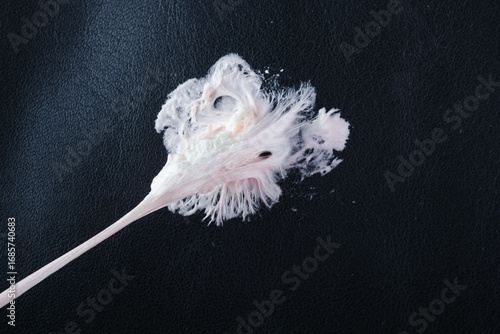 Chewing gum has become stuck on a black leather textured surface, showing its stretching and gooey consistency. Concept of daily stains. Spot-cleaning sticky mess upholstery seating. top view. 