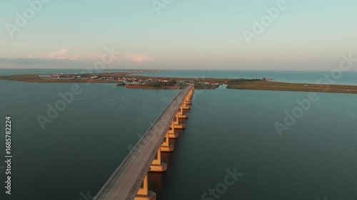 Wallpaper Mural Drone View of Rippling Ocean Lake Water Under Road Bridge Leading to Green Land Island With Pink Sky at Sunset Torontodigital.ca