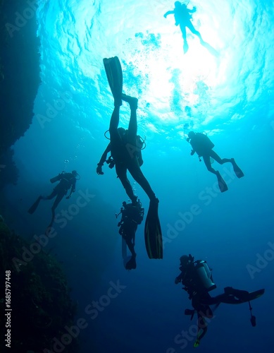 Wallpaper Mural Divers silhouetted in deep blue ocean. Sunlight beams through the water Torontodigital.ca