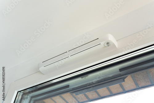 Modern window vent for efficient air supply and comfort. Close-up of trickle vent integrated into a window. Concept of home ventilation, energy-saving design, and climate control technology.