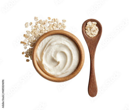 Wooden bowl of creamy porridge, topped with scattered oats and a wooden spoon