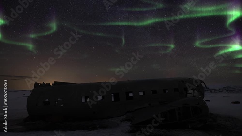 Time lapse of Aurora borealis above a crashed DC-3 Plane in Solheimasandur Iceland during winter. Tourism landmark at night with stars and sky.