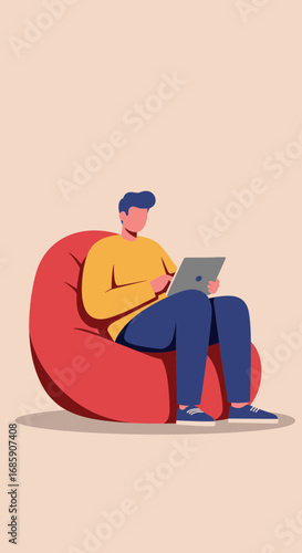 Young man comfortably using a laptop while relaxing on a large red beanbag chair, embracing modern work-life balance.