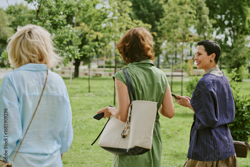 Bilde på lerret Three middle aged Caucasian women walking outdoors in park, holding smartphones