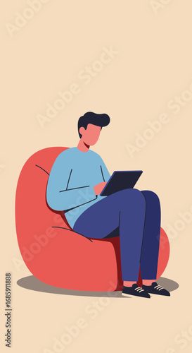 Young man comfortably using tablet device while relaxing on large beanbag chair
