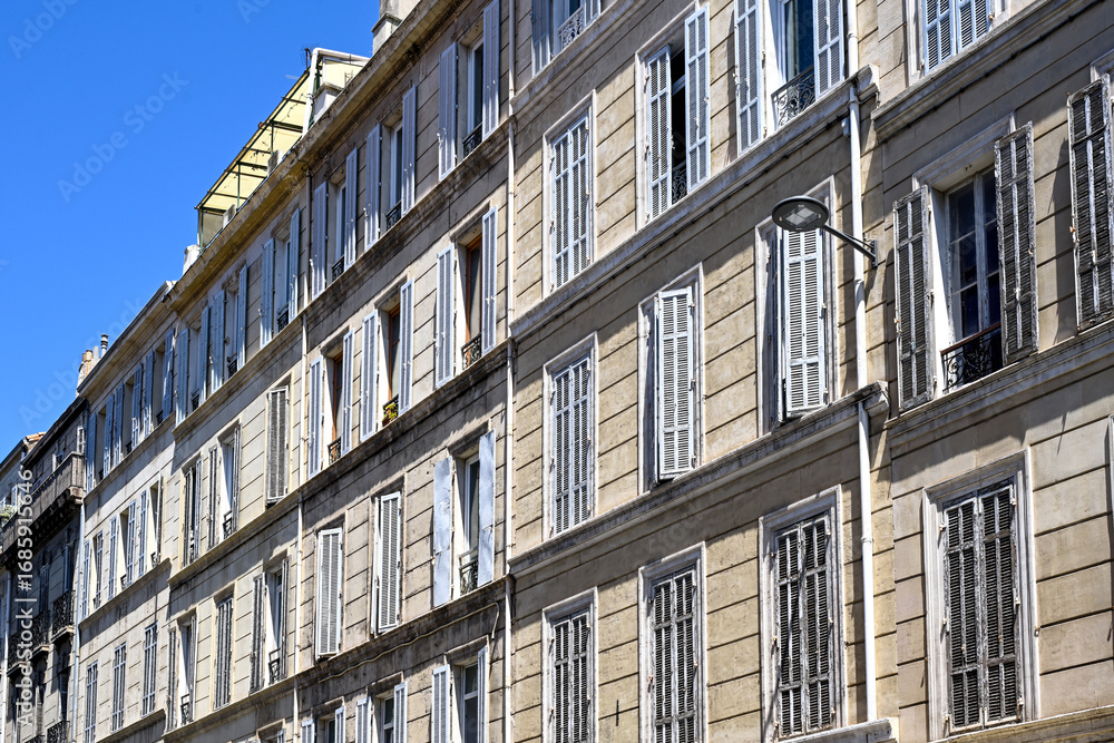 Fototapeta premium Haussmann-style building with old wooden shutters, rue de Lodi, under a deep blue sky. Classic Marseille architecture, Provence, France, rue de Lodi, Marseille