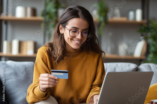Smiling woman using laptop and credit card for online shopping at home