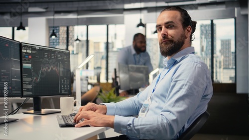 Close up of happy trader in prop firm workplace analyzing market data and executing trades using trading software interface on PC. Joyous stockbroker at work monitoring stock prices