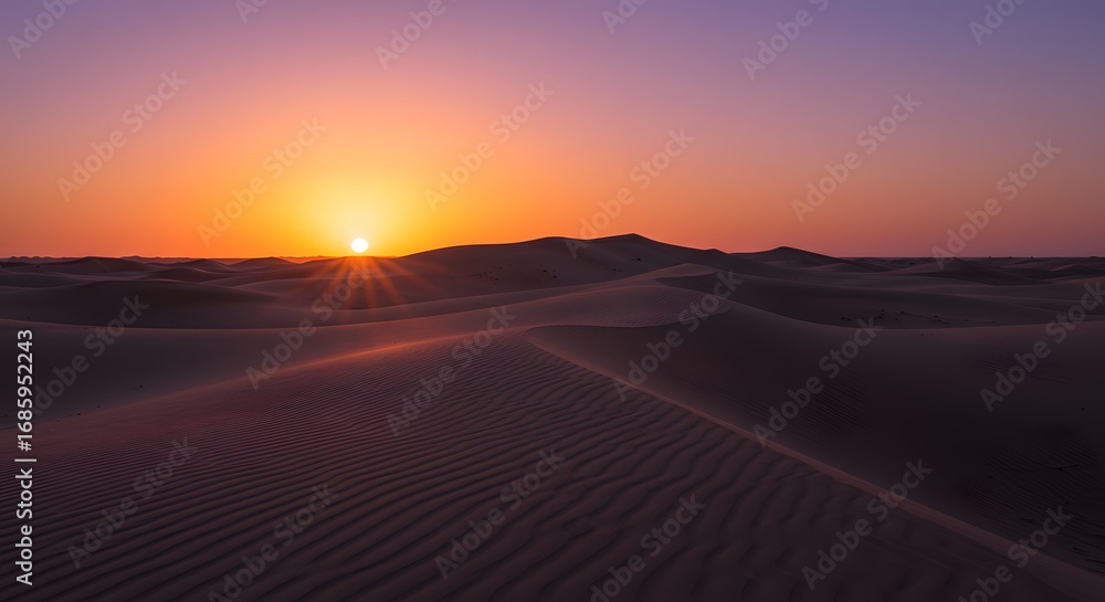 Fototapeta premium Desert horizon ablaze as the sun dips below the dunes, painting the sky in vibrant orange and purple hues.
