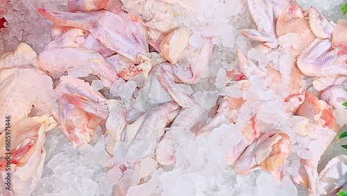 Fresh raw chicken wings displayed on a bed of crushed ice for sale at a market.